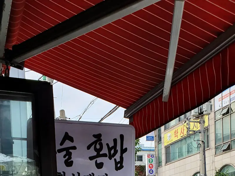 붉은색 스트라이프 어닝 아래 '술 혼밥'이라고 적힌 간판이 보인다.