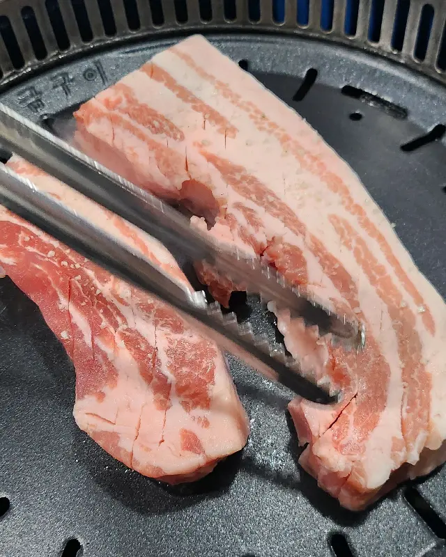 두툼한 삼겹살이 불판 위에서 익어가는 모습