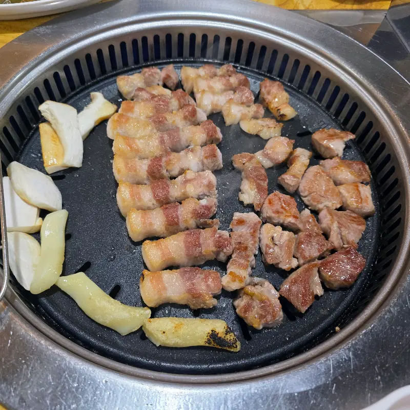 잘 구워진 삼겹살과 구운 김치, 버섯, 떡