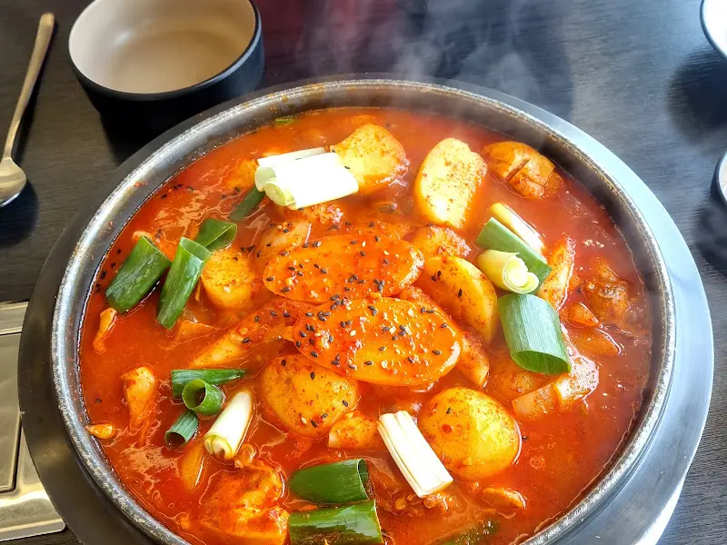 닭볶음탕과 함께 제공되는 기본 반찬들. 김치, 양파절임, 부침개가 정갈하게 담겨있다.