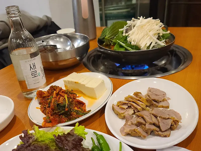 푸짐한 잔치상 차림, 감자탕, 수육, 쭈꾸미 볶음, 김치, 두부 등이 한 상 가득 차려져 있다.