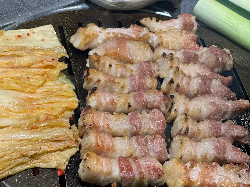 불판 위에 올려진 구운 김치와 삼겹살