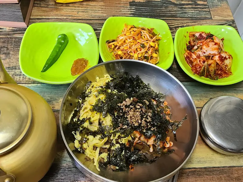 테이블 위에 놓인 묵밥과 반찬, 그리고 따뜻한 육수가 담긴 주전자