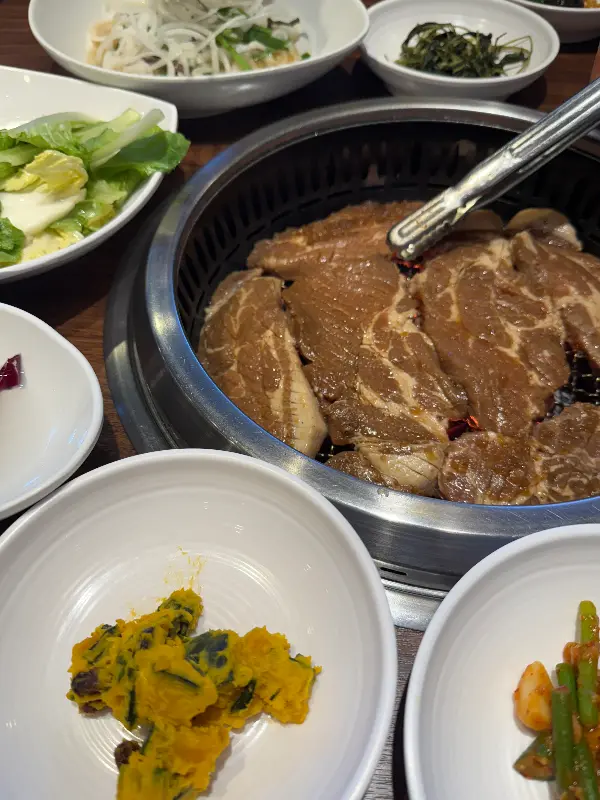 숯불 위에서 익어가는 돼지갈비와 밑반찬