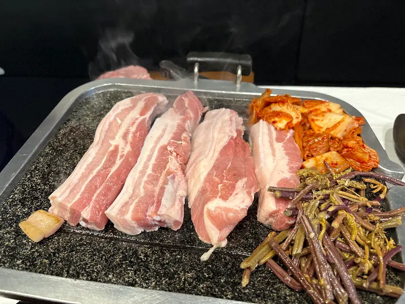 불판 가득 채운 삼겹살, 김치, 고사리