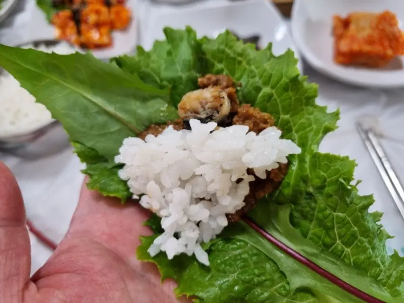 쌈 채소에 밥과 우렁쌈장을 올려 한 쌈