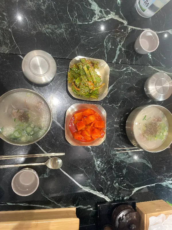 테이블 위에 설렁탕과 얼큰설렁탕, 깍두기, 겉절이, 그리고 물컵 등이 정갈하게 놓여있다.