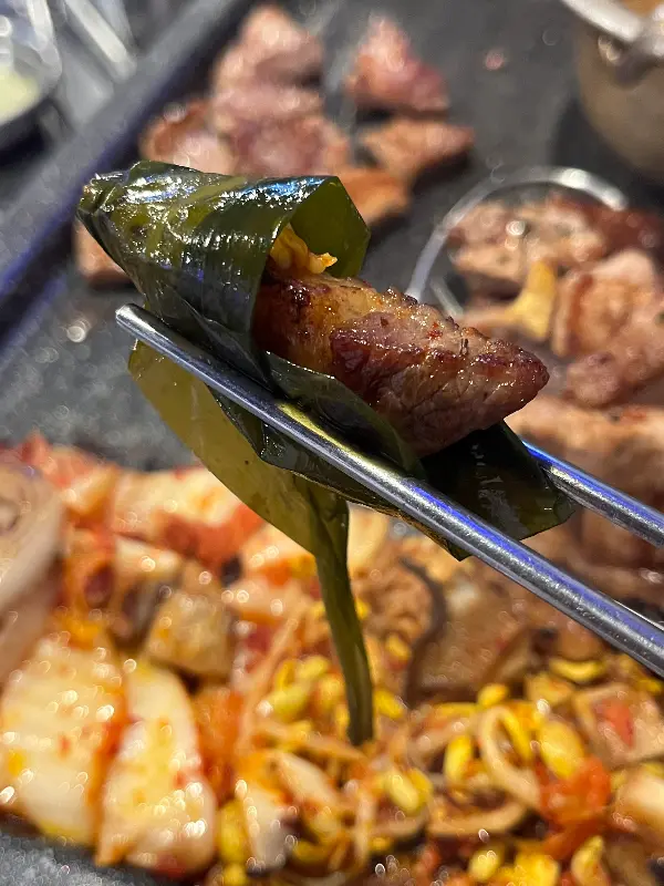 쌈 채소에 고기와 쌈장을 얹어 먹음직스럽게 쌈을 싼 모습