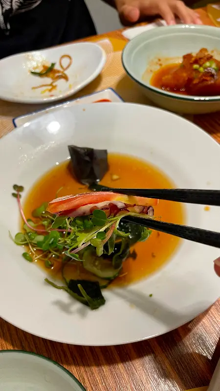 싱싱한 해산물 한 점을 젓가락으로 들어올린 모습