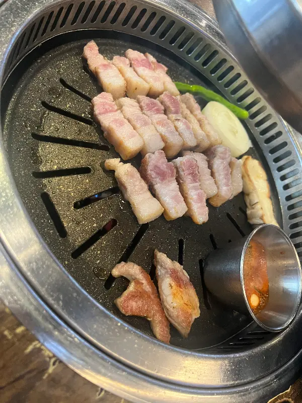 먹기 좋게 잘린 삼겹살이 불판 위에서 노릇하게 익어가는 모습