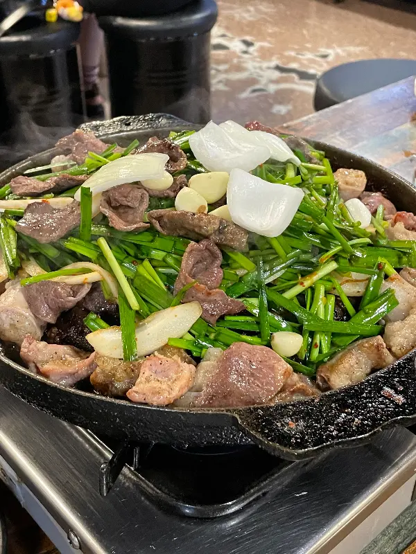 불판 위에서 곱창, 막창, 염통, 부추, 양파, 마늘이 함께 구워지는 모습