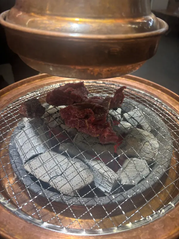 화로 위 석쇠에 붉은 빛깔의 마라 갈비살이 구워지고 있는 모습