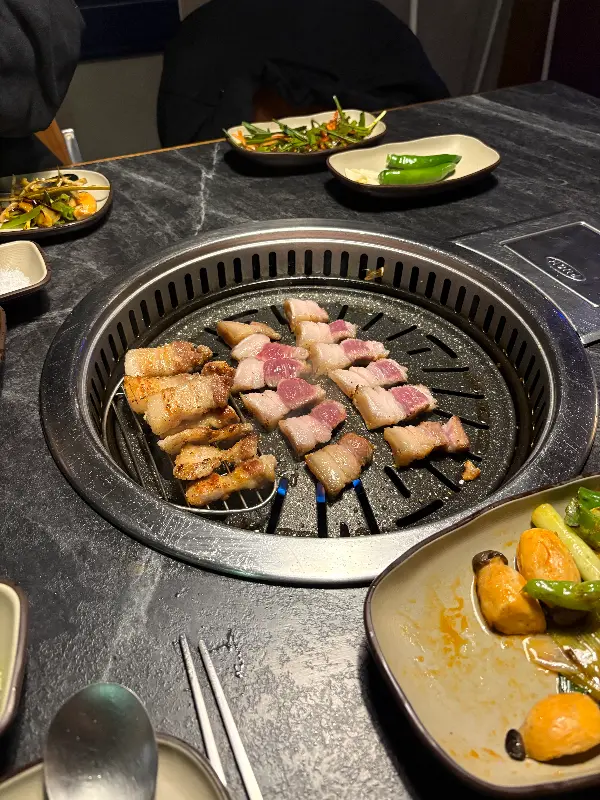 초삼구이에서 제공되는 다양한 밑반찬과 볏짚 삼겹살 구이