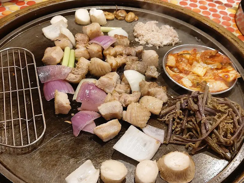 불판 위에 올려진 고기, 양파, 버섯, 김치