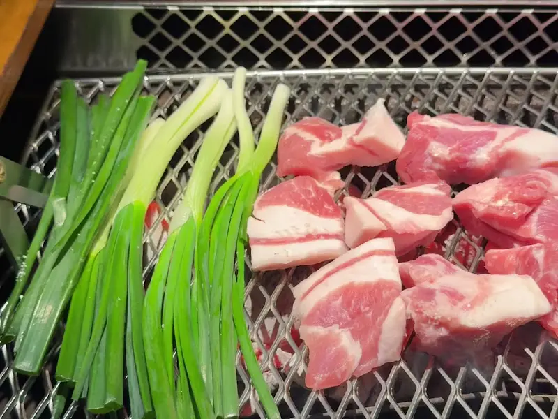 숯불 위에서 구워지는 돼지고기와 쪽파