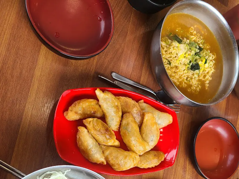 테이블 위에 놓인 붉은 접시 위의 군만두와 라면 그릇