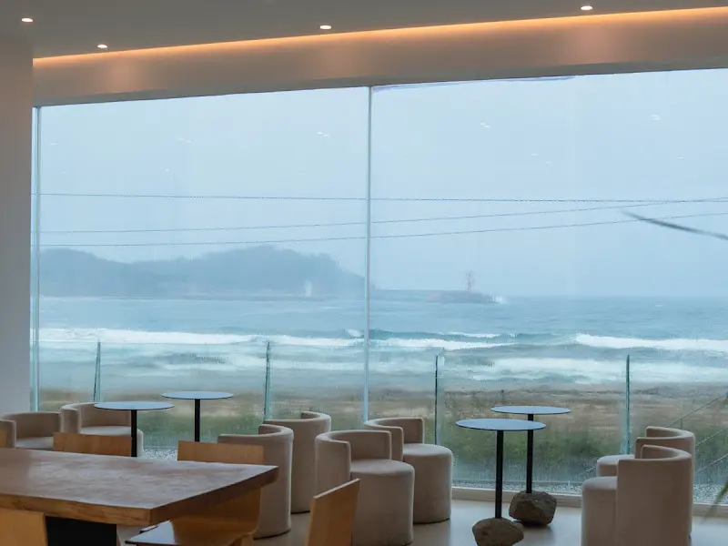 카페 내부 좌석과 통창 밖 바다 풍경