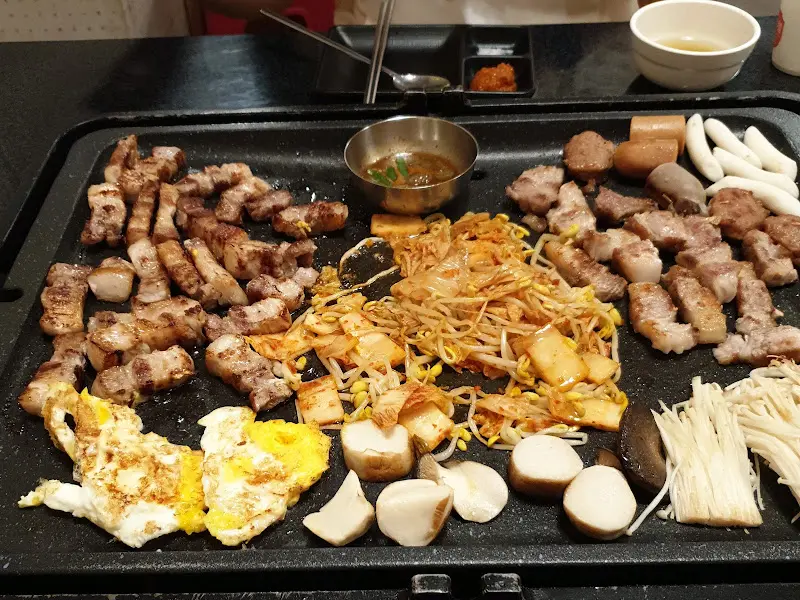 돌판 위에 구워진 삼겹살, 햄, 버섯, 떡갈비, 떡