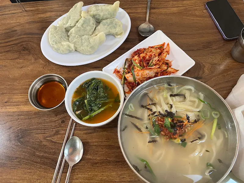 만두, 칼국수, 김치, 열무김치가 함께 있는 전체 샷