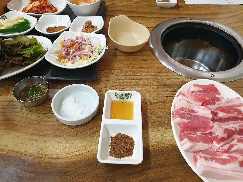 테이블 가득 차려진 밑반찬과 삼겹살