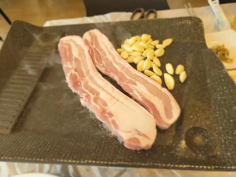 불판 위에서 지글거리는 삼겹살과 마늘