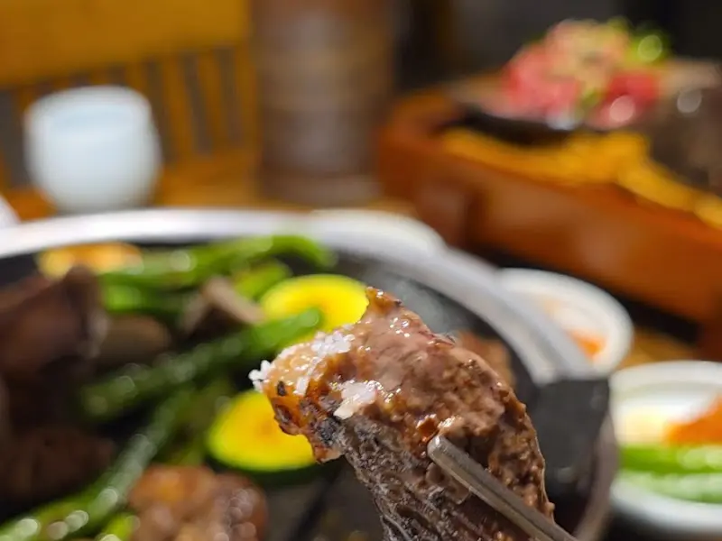 젓가락으로 집어든 흑염소 갈비 한 점