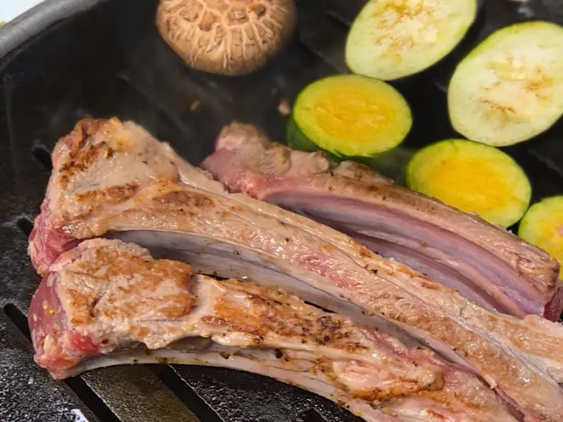 숯불 위에 구워진 흑염소 갈비와 채소