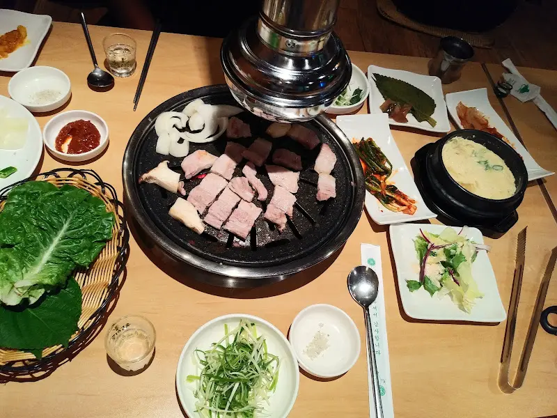 숯불 위에 구워지고 있는 돼지고기와 푸짐한 밑반찬