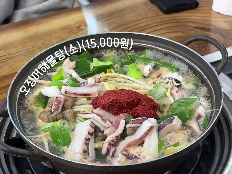 오징어해물탕 (소) - 뽀얀 국물 위에 오징어, 콩나물, 붉은 양념장이 얹혀있다.