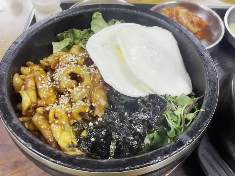 낙지 비빔밥의 클로즈업 사진. 탱글탱글한 낙지와 윤기 흐르는 양념이 인상적이다.