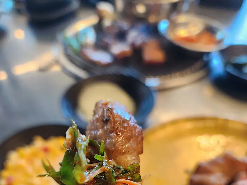 잘 익은 흑돼지 한 점을 집어 올린 모습. 윤기가 흐르고 쫄깃한 식감이 느껴진다.