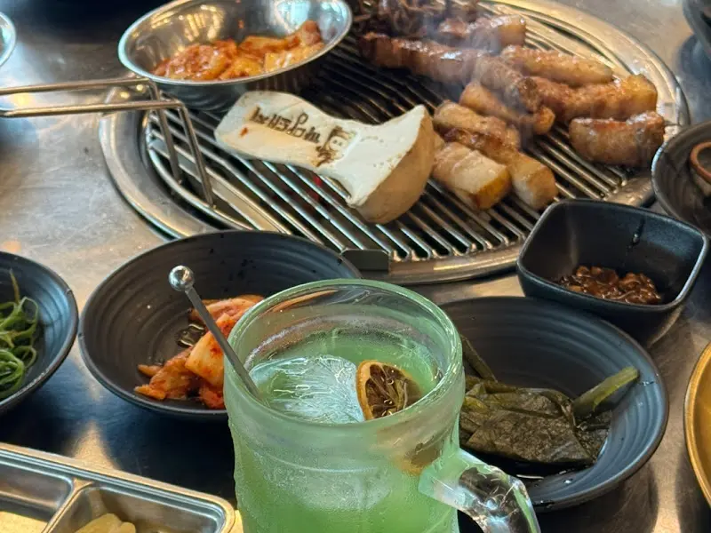 다양한 밑반찬과 흑돼지가 함께 놓여 있는 테이블 전경.