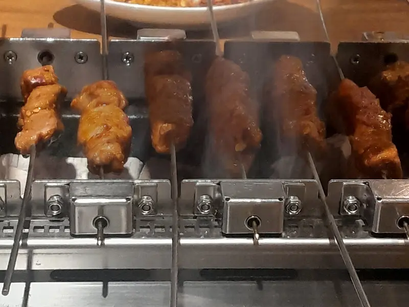 자동으로 돌아가는 꼬치 구이 기계 위에 올려진 양꼬치