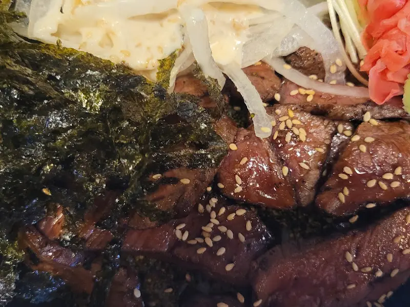 스테이크 덮밥 클로즈업 사진. 스테이크 위에 뿌려진 깨가 눈에 띈다.