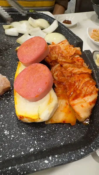 불판 위에 김치와 소세지가 함께 구워지고 있는 모습