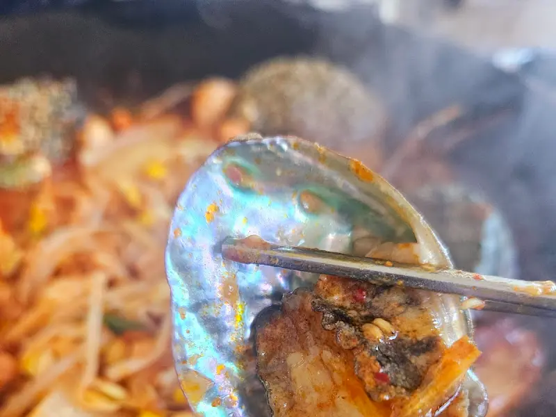 전복 껍데기를 집게로 들어올린 모습