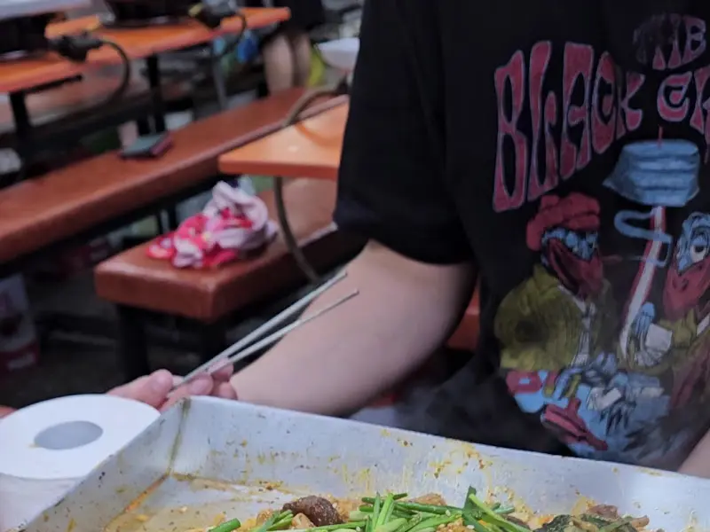 철판에 가득 담긴 양념순대와 젓가락을 든 손