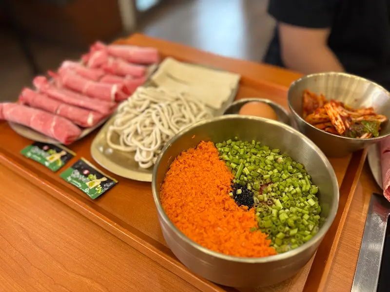 샤브샤브 재료와 흑미 칼국수 면, 김치, 볶음밥 재료가 한 상 가득 차려진 모습