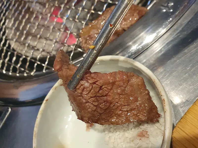 잘 구워진 갈비살을 소스에 찍어 먹는 모습