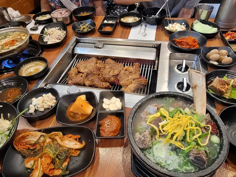 갈비, 샐러드, 솥밥 등 다양한 메뉴가 테이블 위에 가득 차려진 모습