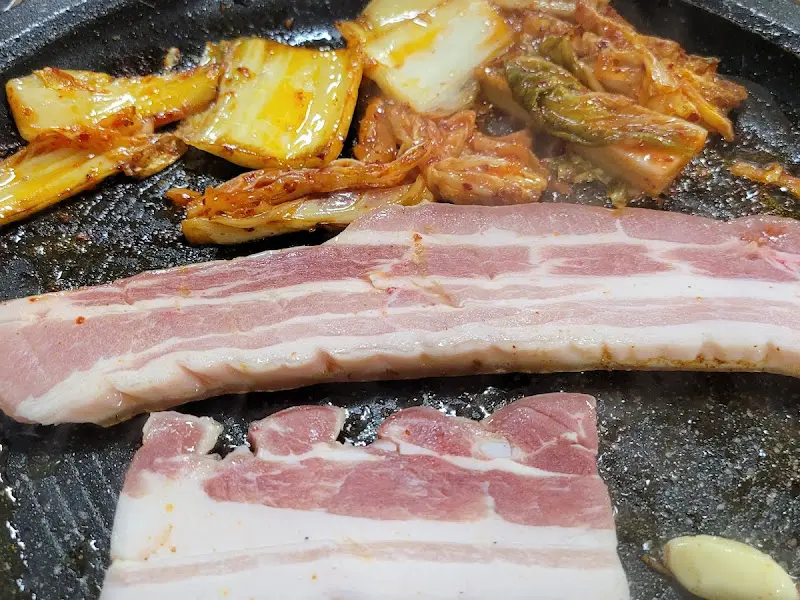 불판 위에서 익어가는 삼겹살과 김치