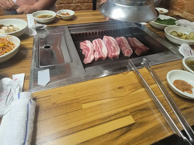 테이블 가득 차려진 밑반찬과 삼겹살
