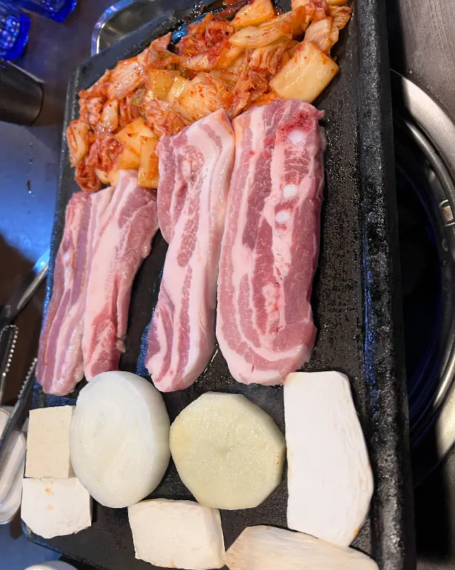 삼겹살, 김치, 떡, 양파, 두부가 함께 구워지는 모습