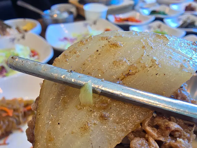 윤기가 흐르는 보쌈을 젓가락으로 집어 올린 모습