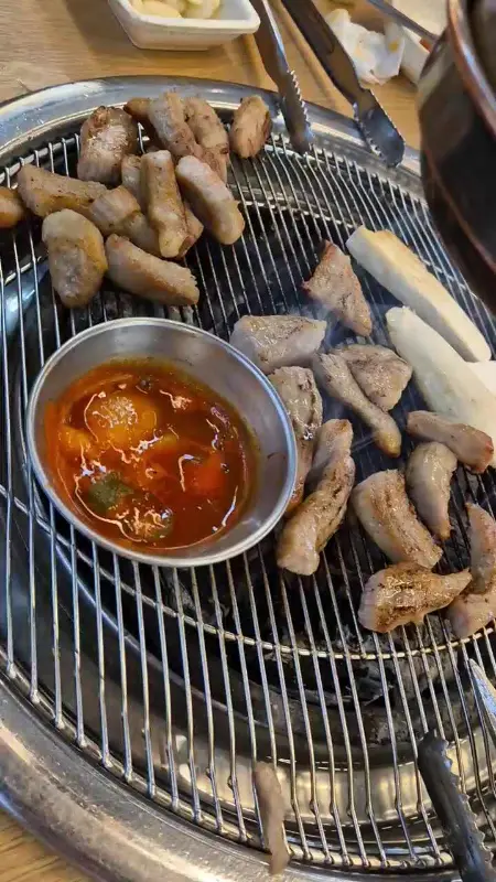 맛있게 구워진 고기를 멜젓에 찍어먹는 모습