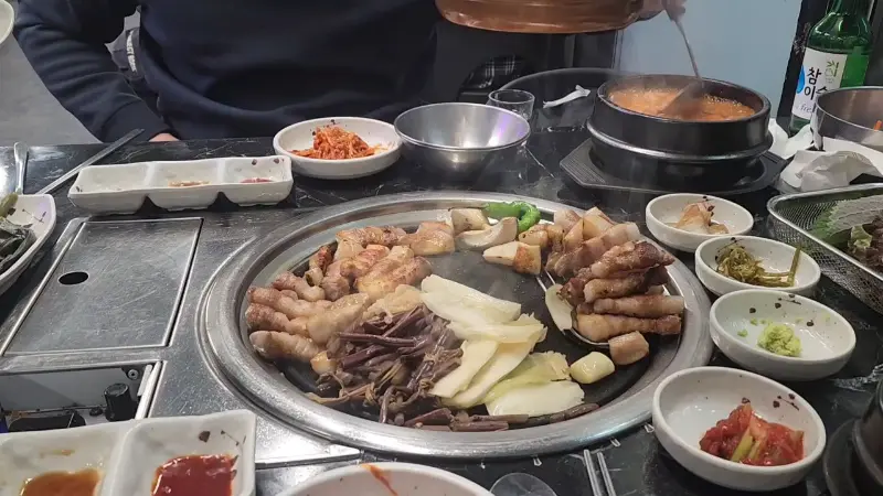 불판 위에 올려진 삼겹살, 미나리, 떡