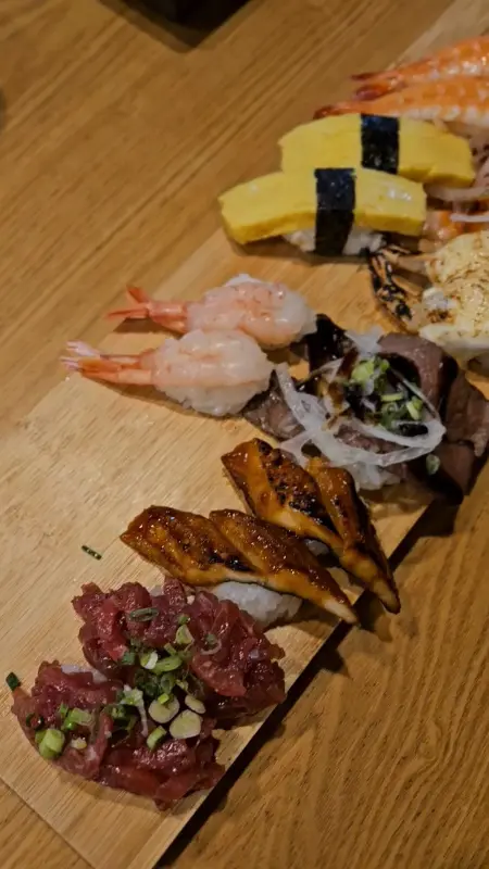 다채로운 초밥이 나무 도마 위에 정갈하게 놓여 있는 모습