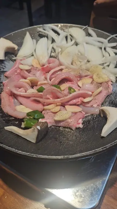 불판 위에 곰장어, 양파, 버섯 등이 푸짐하게 올려져 있는 모습