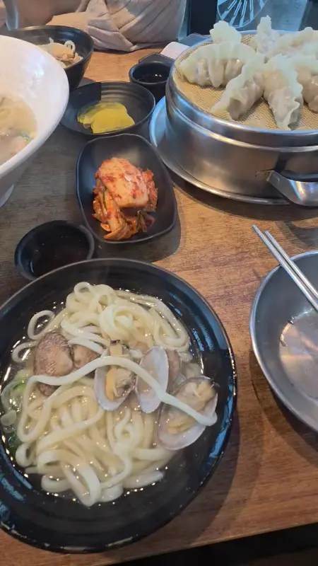 해물바지락칼국수와 만두, 김치가 놓인 테이블