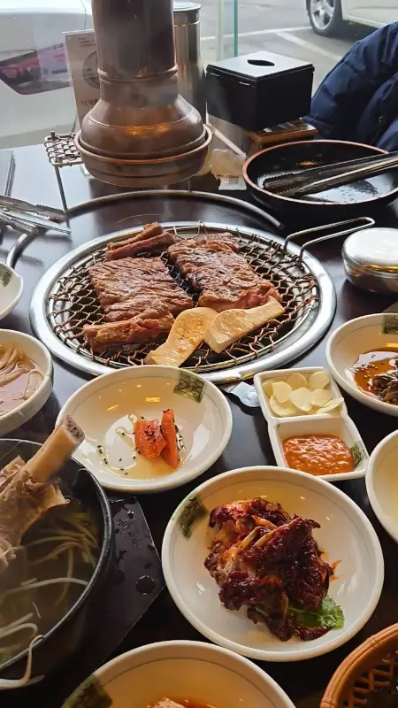 숯불 위에 구워지는 갈비와 푸짐한 밑반찬